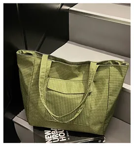 Detailansicht der grünen karierten Nylon-Tragetasche mit Fronttasche und langen Riemen