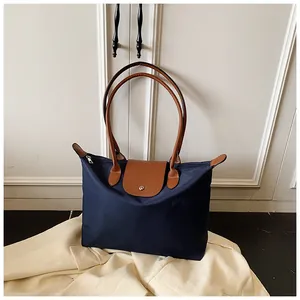 Détail d'un sac cabas en nylon bleu foncé avec rabat cuir et fermoir pression