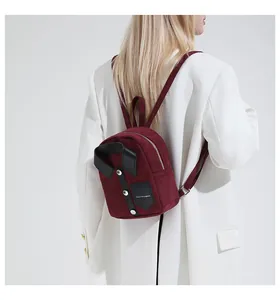 Close-up of burgundy suede mini backpack with shirt collar design and silver buttons