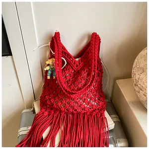 Detail van rode macramé draagtas met lange franjes en een popvormige hanger