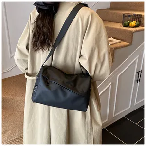 Détail d'un grand sac bandoulière noir en tissu oxford sur modèle avec sangle réglable