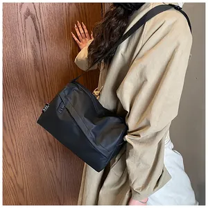 Détail du sac bandoulière en nylon noir montrant la sangle réglable et le tissu résistant