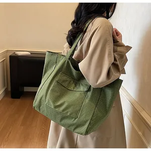 Detail einer großen grünen karierten Nylontasche mit Seitenfalte und Vordertasche