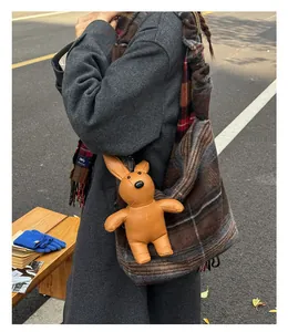 Detail of a large plaid tote bag with a brown leather rabbit charm and winter outfit