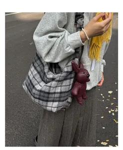 Detail of grey plaid hobo bag with a red leather rabbit charm and spacious interior