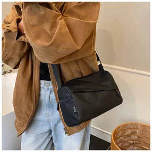 Détail de la bandoulière large réglable et de l'étiquette logo sur le sac en nylon noir