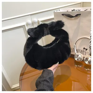 Detail of black plush handbag with large velvet bow and metallic zipper closure