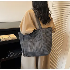 Detailansicht der großen schwarz-weiß karierten Nylon-Einkaufstasche mit Vordertasche an der Schulter