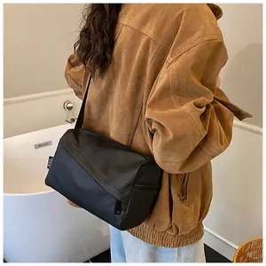Détail du grand sac bandoulière noir en tissu Oxford montrant le logo et la texture durable
