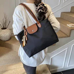 Grand sac cabas en nylon noir avec anses en cuir marron et pompon en perles sur l'épaule