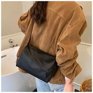 Détail du sac bandoulière minimaliste en nylon noir avec une étiquette tissée sur le côté