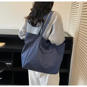 Detailansicht der großen blau-weiß karierten Nylon-Tragetasche an einem weiblichen Model