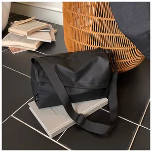 Détail d'un sac bandoulière en tissu oxford noir avec sangle réglable sur un livre