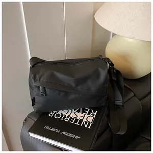Gros plan détaillé d'un sac bandoulière en tissu oxford noir sur un canapé en cuir