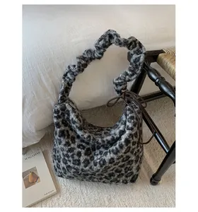 Detail of plush leopard print handbag featuring a ruffled handle and side ribbon bow