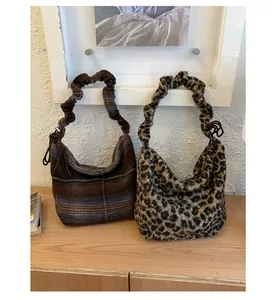 Detail view of large plaid and leopard print hobo bags with ruffled shoulder straps