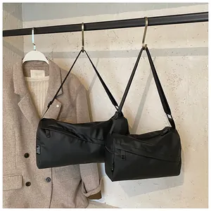 Détail du sac bandoulière noir en oxford avec fermeture éclair diagonale et étiquette