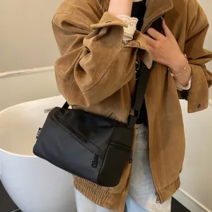 Sac bandoulière en tissu Oxford noir avec large sangle réglable dans un décor décontracté