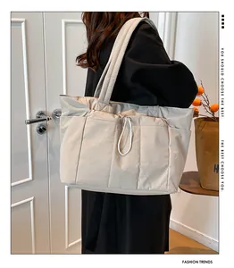 Detailed side view of beige quilted tote bag with side pockets and drawstring design