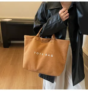 Detailed macro shot of a brown suede tote bag featuring white TOTE BAG lettering