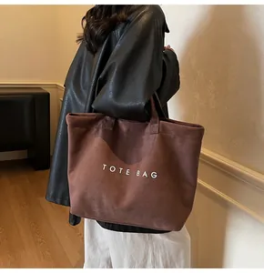 Brown suede tote bag with letter print shown on model for a casual commute look