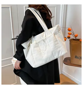 Detail view of large white down tote bag with drawstring pocket on a model