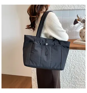 Detail of black nylon tote bag featuring drawstring lock and quilted shoulder strap