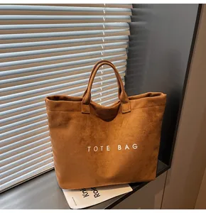 Detail of a brown suede tote bag with white TOTE BAG lettering in a sunny window setting