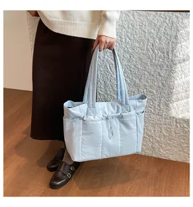 Detail view of light blue quilted tote bag with drawstring pocket and nylon texture