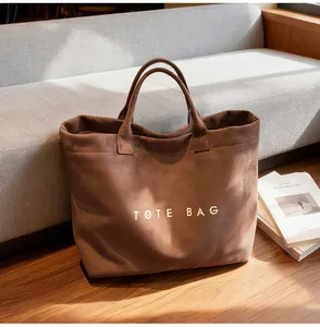 Detailed view of large coffee brown suede tote bag with white TOTE BAG lettering text