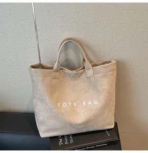 Macro detail of the beige suede tote bag showing texture and white TOTE BAG lettering