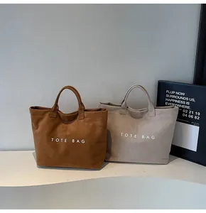 Macro detail of high-capacity tote bags in brown and beige with matte suede finish
