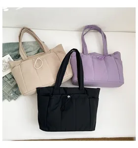 Detailed macro view of quilted nylon tote bags in khaki, purple, and black colors