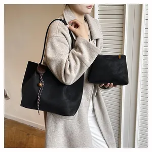 Detail of a black matte tote bag set with a textured bag charm and matching pouch