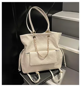 Dettaglio della borsa tote avorio trapuntata con catena dorata su libri di design