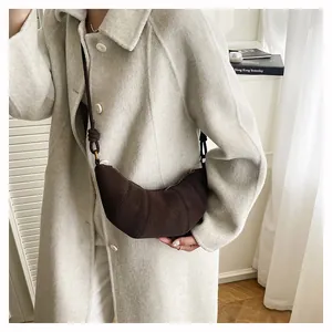 Détail du sac croissant en daim marron foncé montrant la structure plissée et le nœud