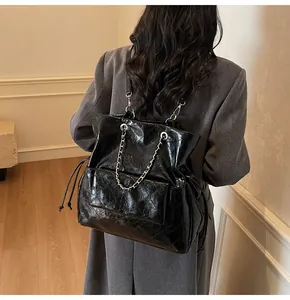 Detail of black quilted leather tote with silver chain handle and drawstring closure