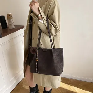 Brown faux suede tote bag with fringe charm worn with a stylish khaki trench coat