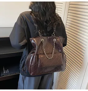 Dettaglio della texture in pelle trapuntata marrone scuro con catena d'argento sulla borsa