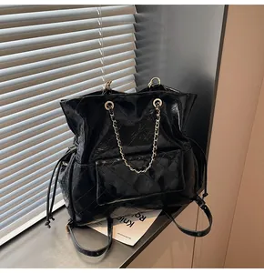 Close-up of black quilted patent leather tote with chain strap and drawstring detail