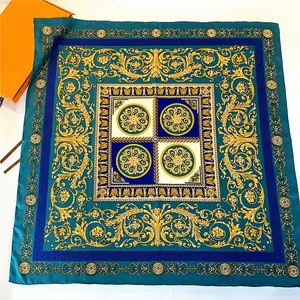 Detailed view of luxury silk scarf featuring golden Baroque floral patterns and blue Greek key