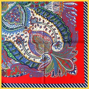 Macro detail of the paisley pattern on a red silk scarf with navy striped edges