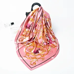 Pink 90cm silk scarf with gold baroque patterns and roses draped on a leather bag
