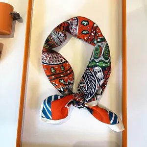 Close-up of silk square scarf with orange floral pattern in elegant gift box