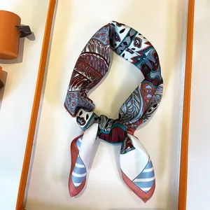 Macro detail of silk twilly scarf with paisley floral prints in a luxury orange gift box