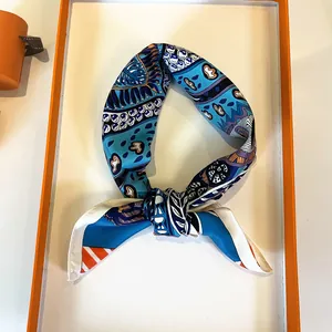 Macro detail of luxury silk scarf with blue paisley pattern in premium orange gift box