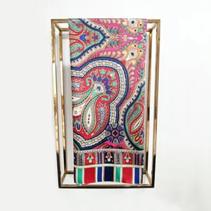 Detail of vibrant paisley floral silk scarf hanging on a minimalist gold metal rack