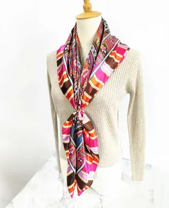Detail of bohemian paisley silk scarf with gold buckle on a beige pleated shirt