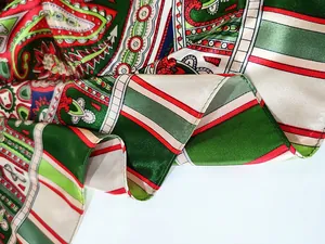 Detail of satin fabric showing green paisley pattern and fine rolled hem edge