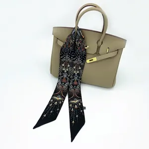 Floral print black twilly silk scarf tied on a beige leather handbag handle